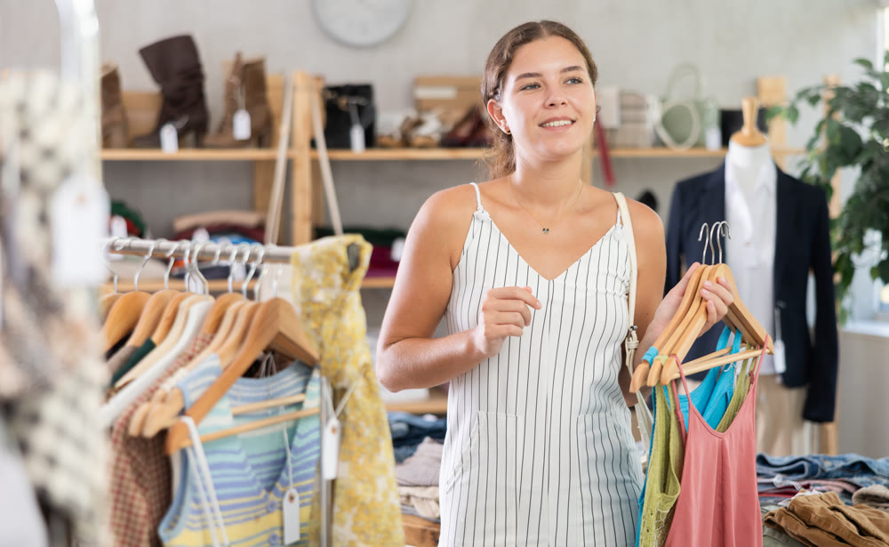 Young woman choosing summer clothes in store