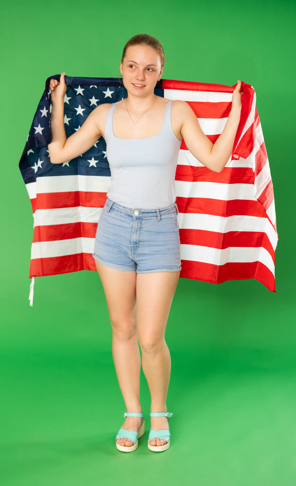 woman in casual clothes holding the flag of the United States of America against of chroma key