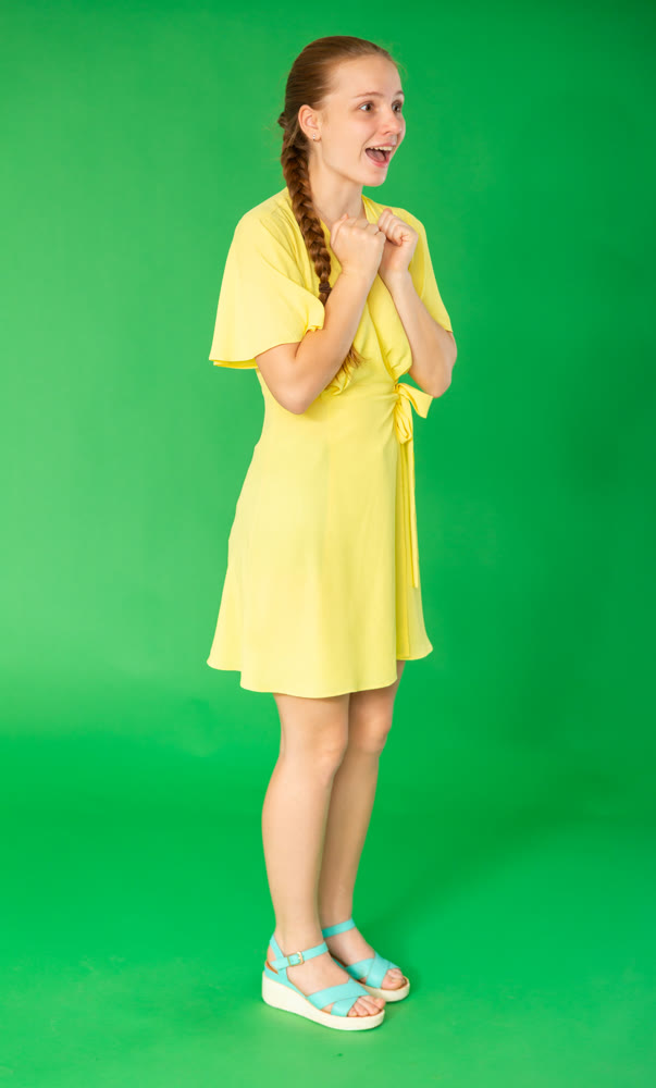 girl stands in a yellow dress and have fun against the background of chromakey