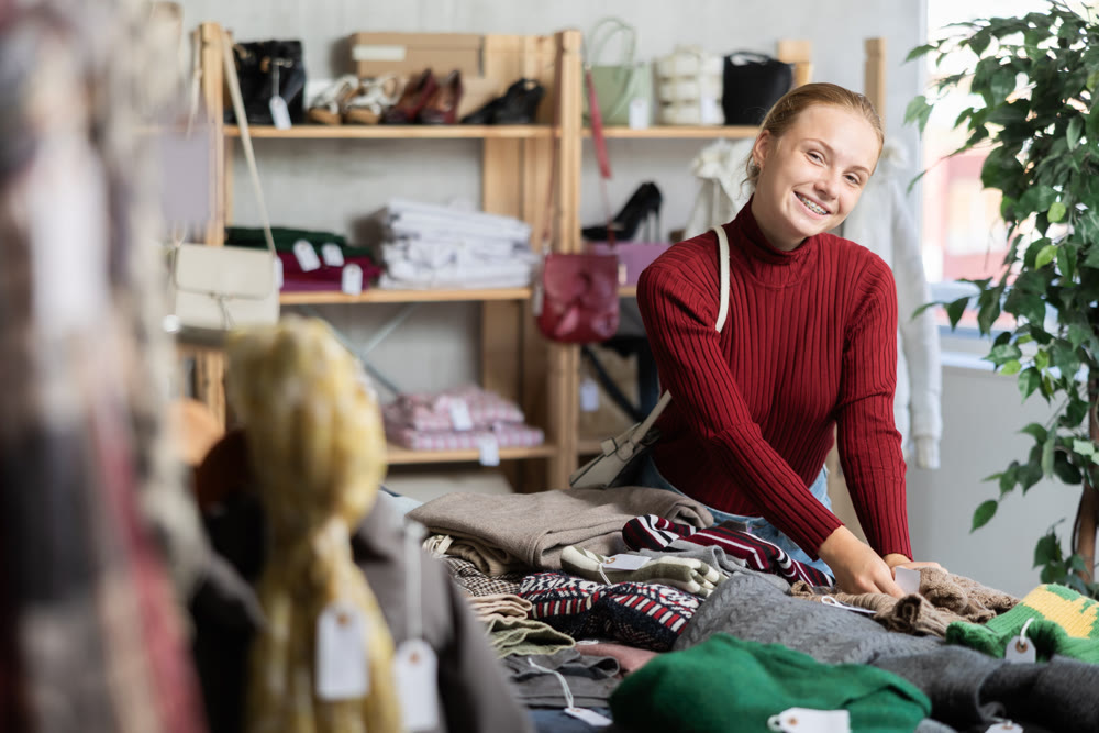 While shopping, teen girl browsing goods items and choose elect warm jumper in store