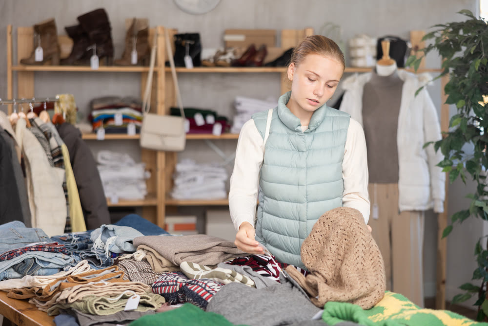 While shopping, teen girl browsing goods items and choose elect warm jumper in store