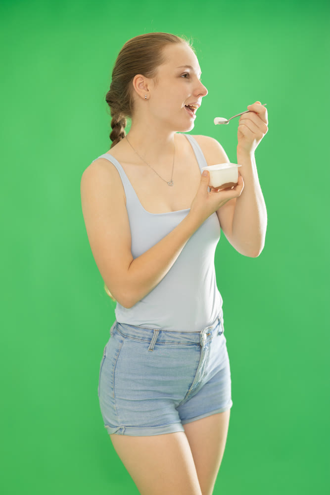 Teenage girl in blue top eats yogurt