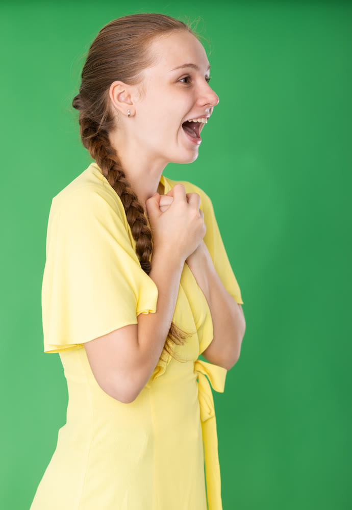 girl stands in a yellow dress and have fun against the background of chromakey