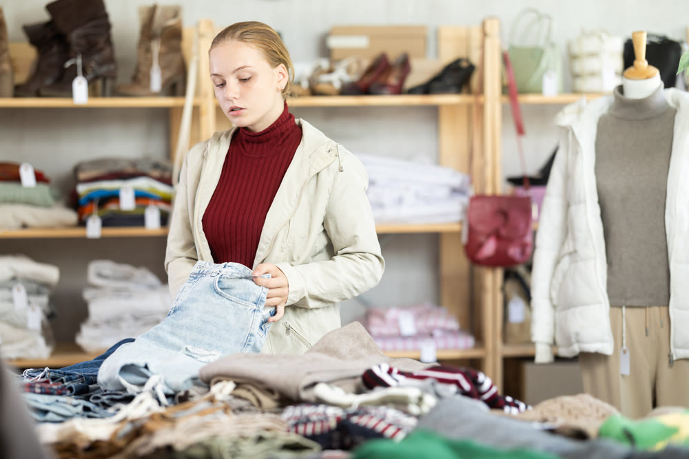While shopping, teen girl browsing goods items and choose elect denim trousers in store