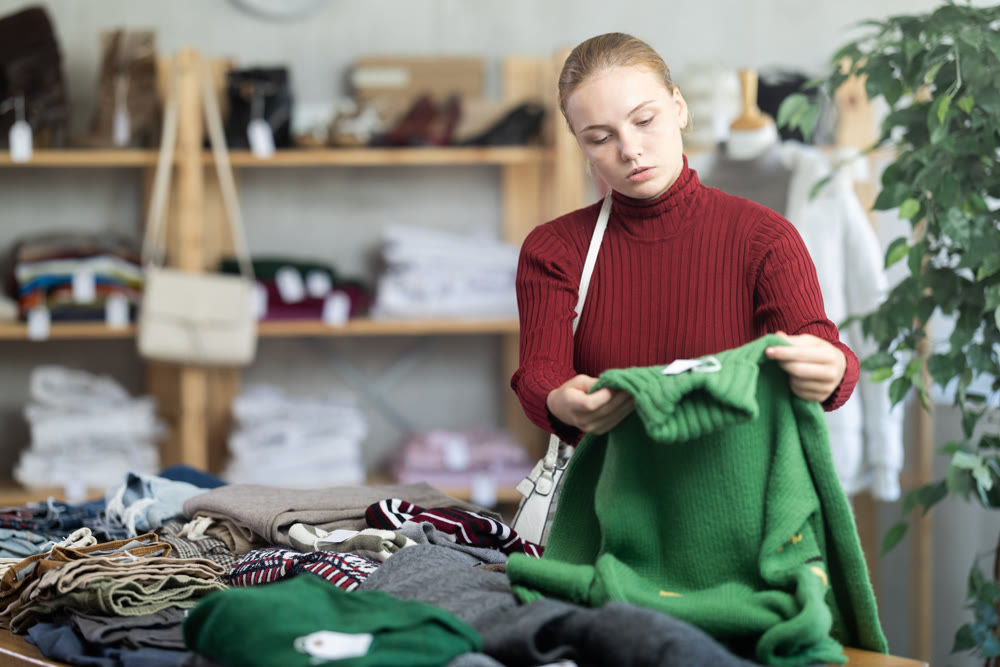 While shopping, teen girl browsing goods items and choose elect warm jumper in store