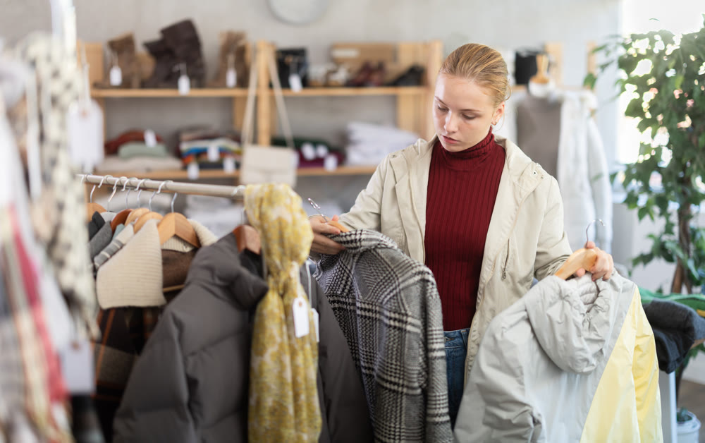 While shopping, teen girl browsing goods items and choose elect something warm outerwear in store