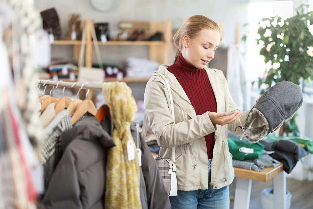 While shopping, teen girl browsing goods items and choose elect fur hat in store