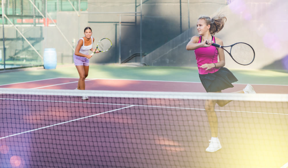 Tennis game - girl actively kicks the ball during tennis game