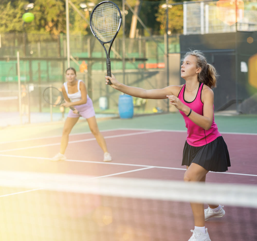 Girl playing tennis ball friendly match on outdoors court