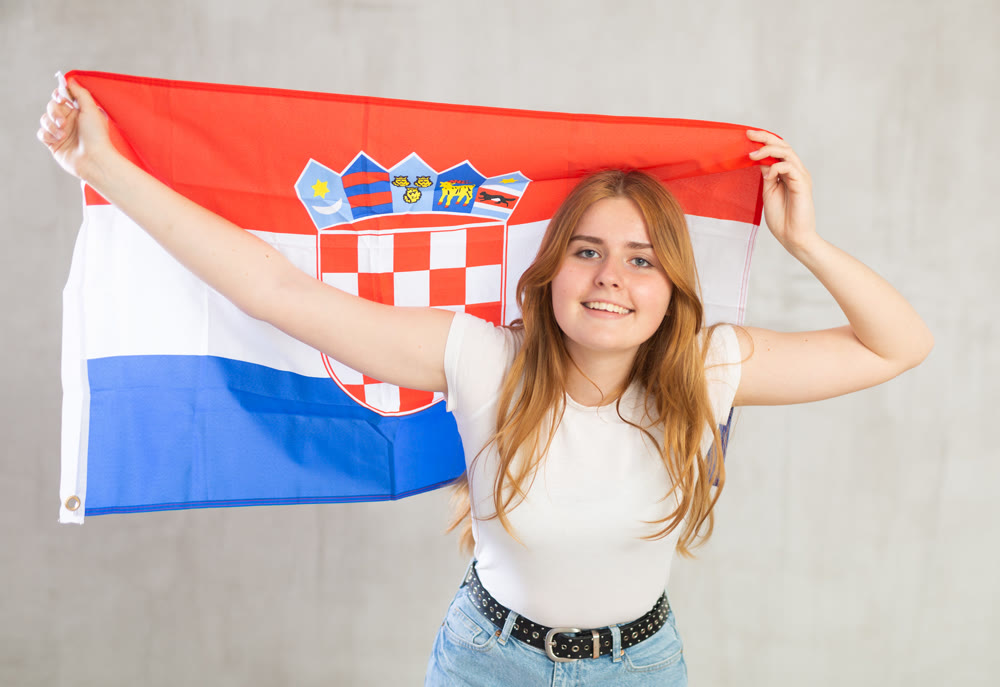 smiling girl in arms raised above head holds cloth of national flag of Croatia