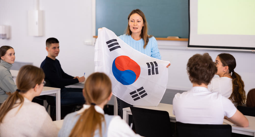 High school teacher holds the flag of South Korea in her hands and talks about this country in geography lesson