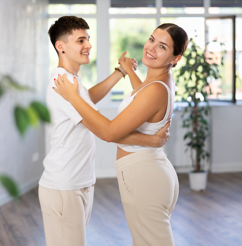 People in pair learning to dance waltz in modern studio