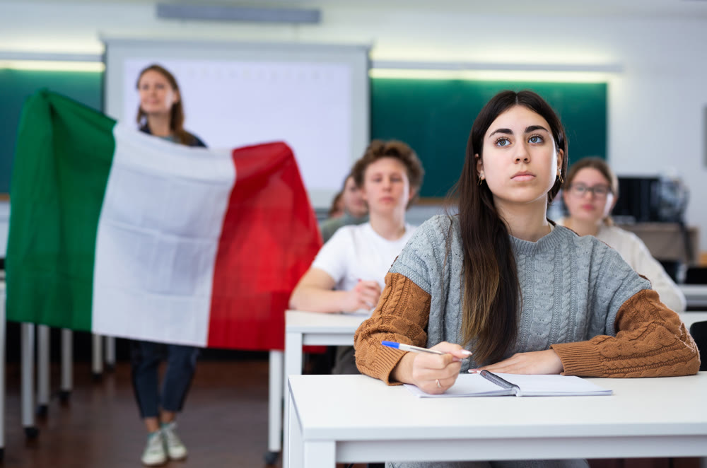 High school teacher tells students about Italy and holds a Italy flag in hands.