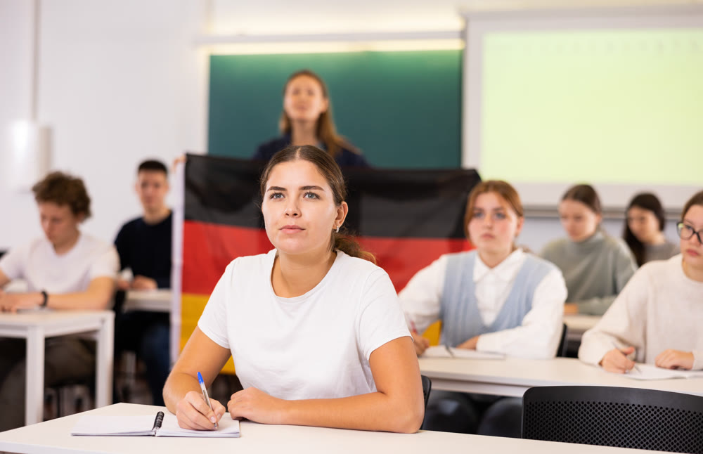 Teacher stands behind students with German flag