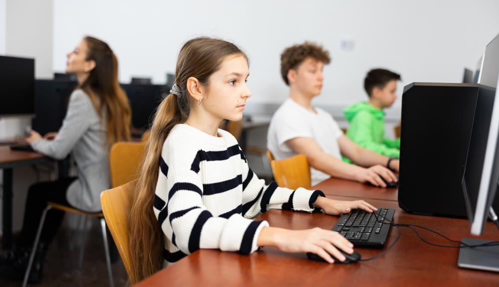Pupils using computers at lesson, teacher teaching them in class room