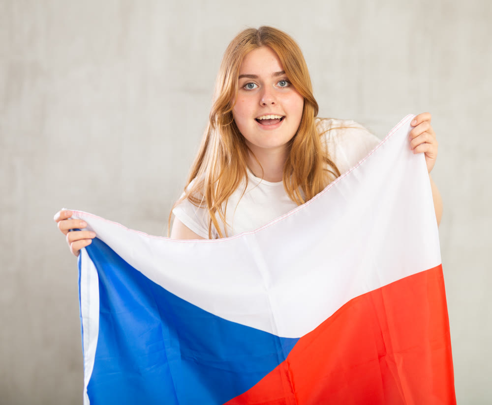 smiling girl in arms raised above head holds cloth of national flag of Czechia