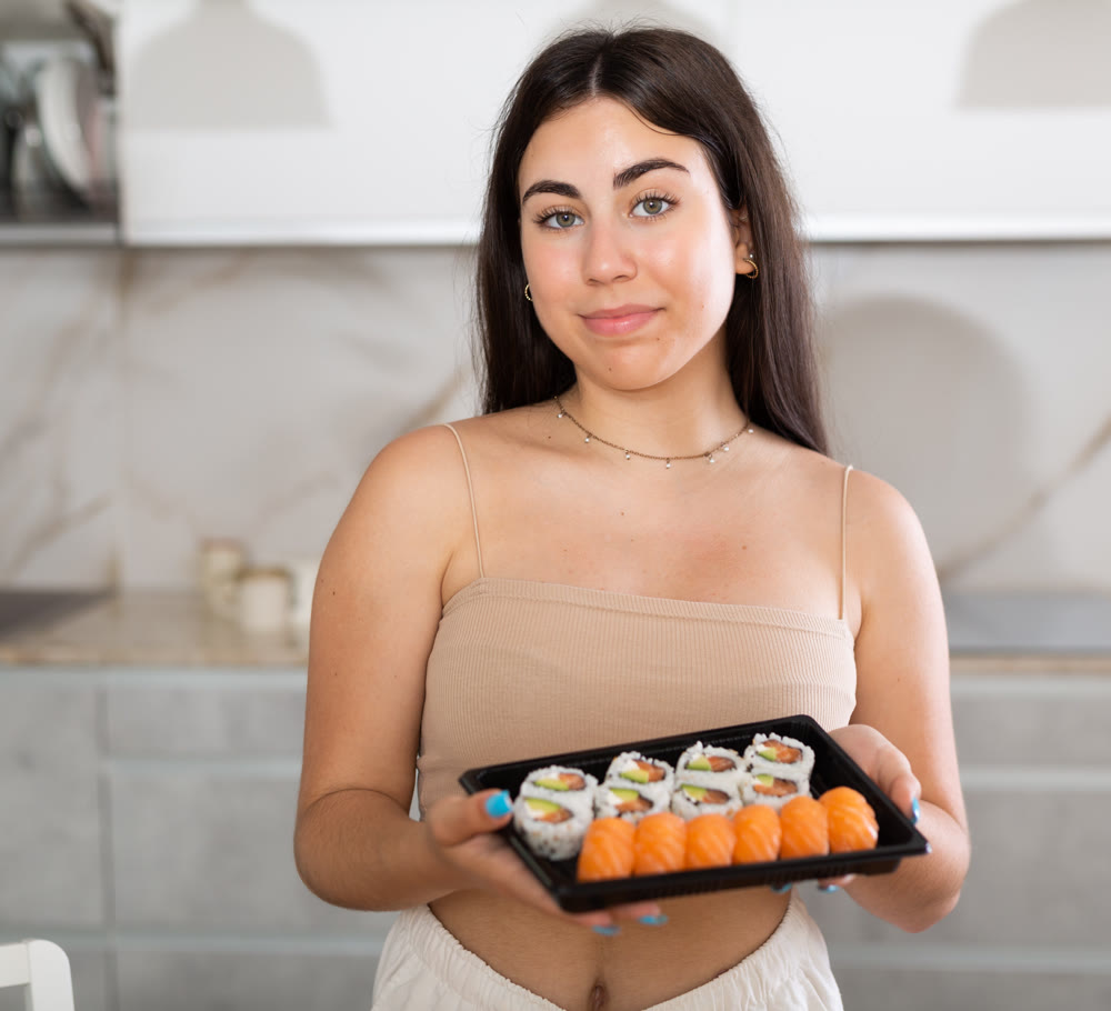 Young woman posing with set of rolls in kitchen