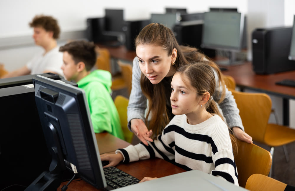 Teacher together with students conduct lesson on computer education