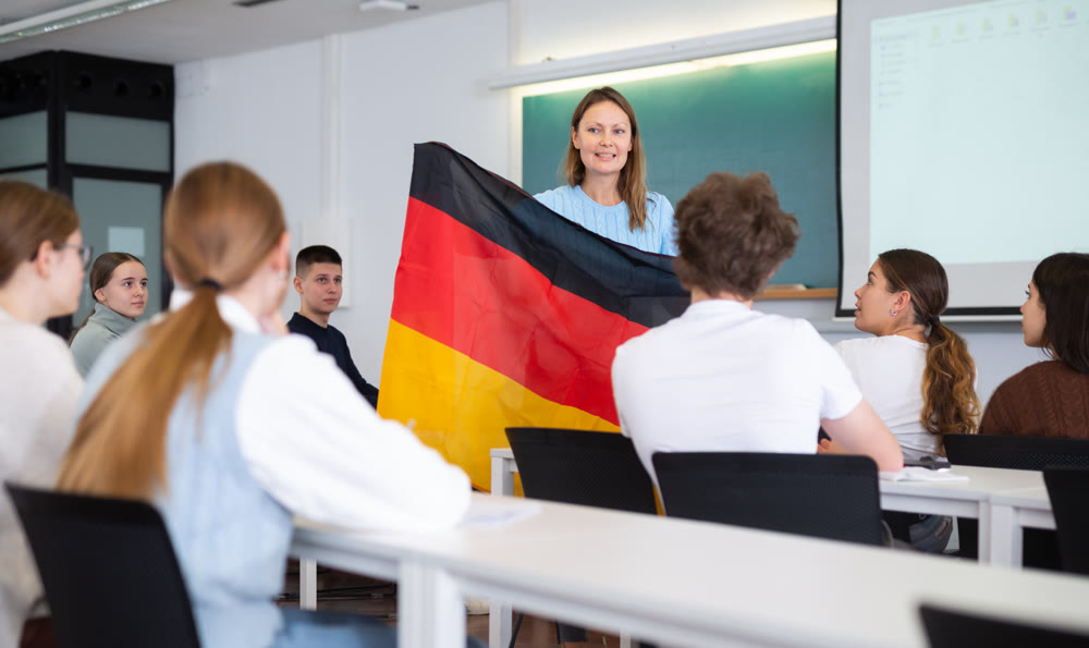 High school teacher holds the flag of Germany in her hands and talks about this country in geography lesson