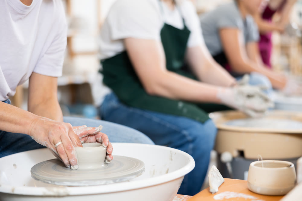 Hands of potters making a clay jug close up