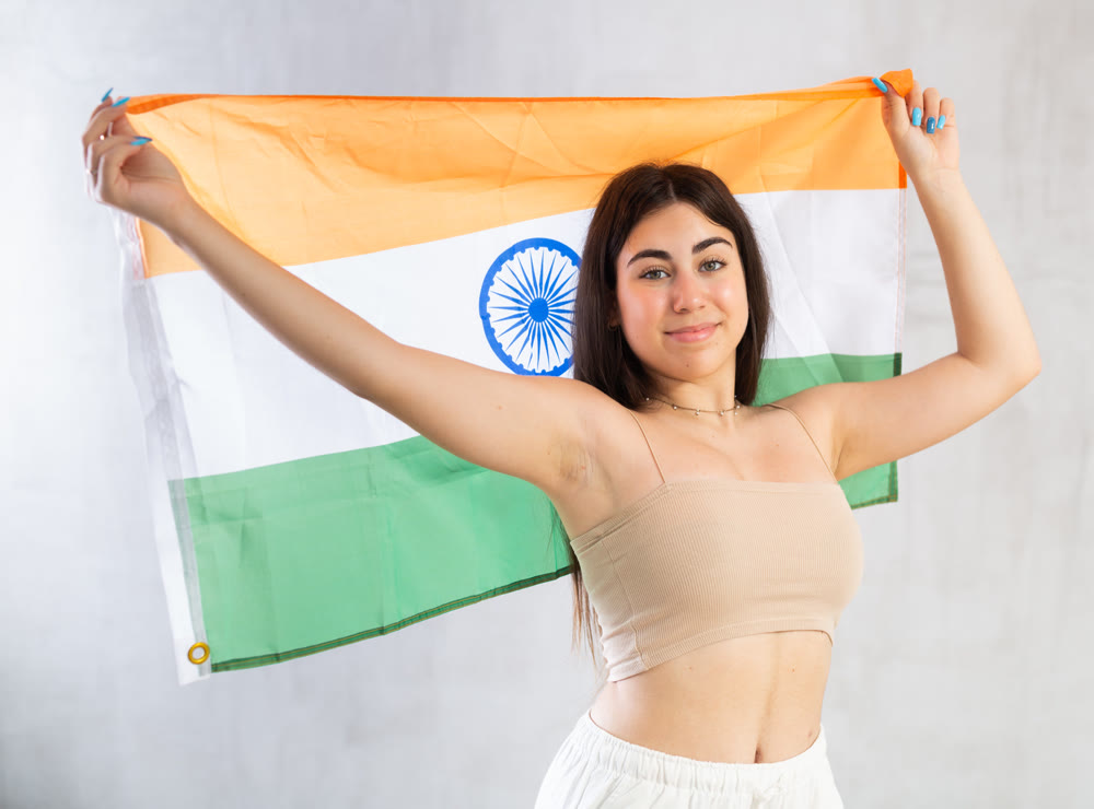 Happy young woman with flag of India against unicoloured background