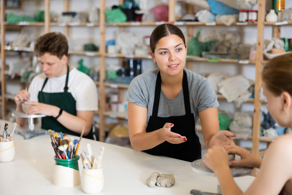Potter teaches teenagers how to make pottery out of clay in workshop