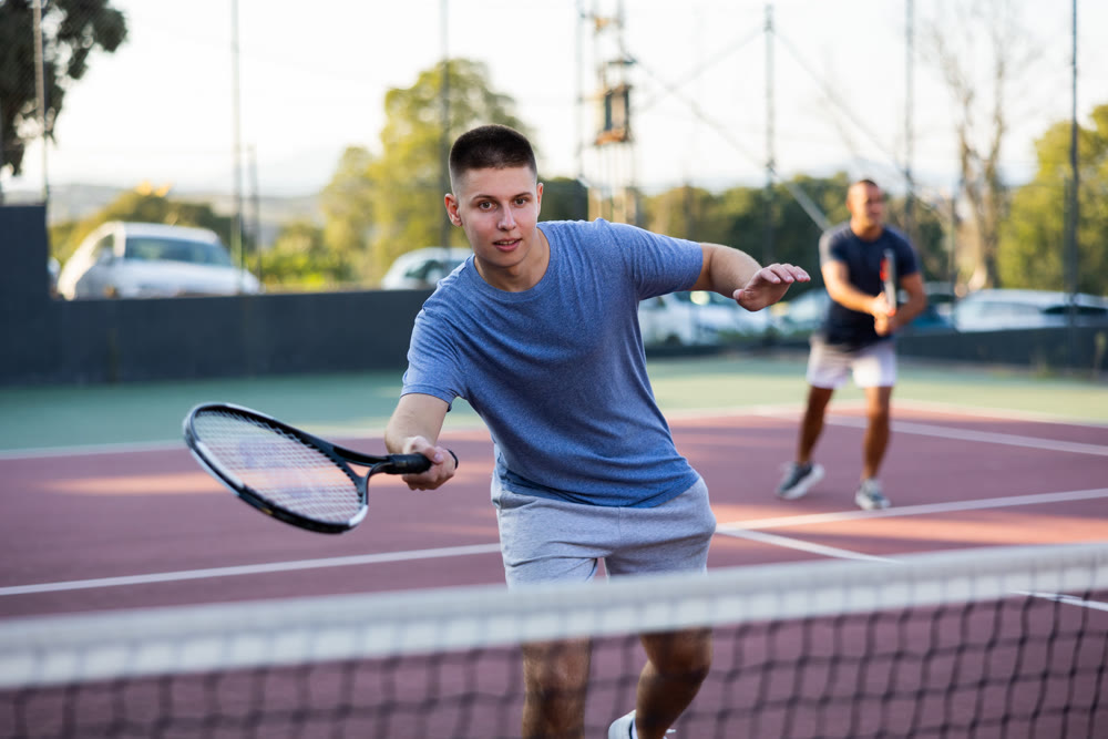 Sports active man during friendly doubles couple match. Two men playing together tennis