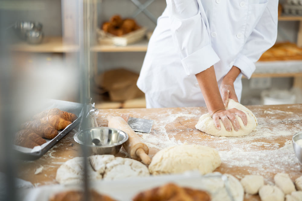 Female hands kneading dough on table, closeup