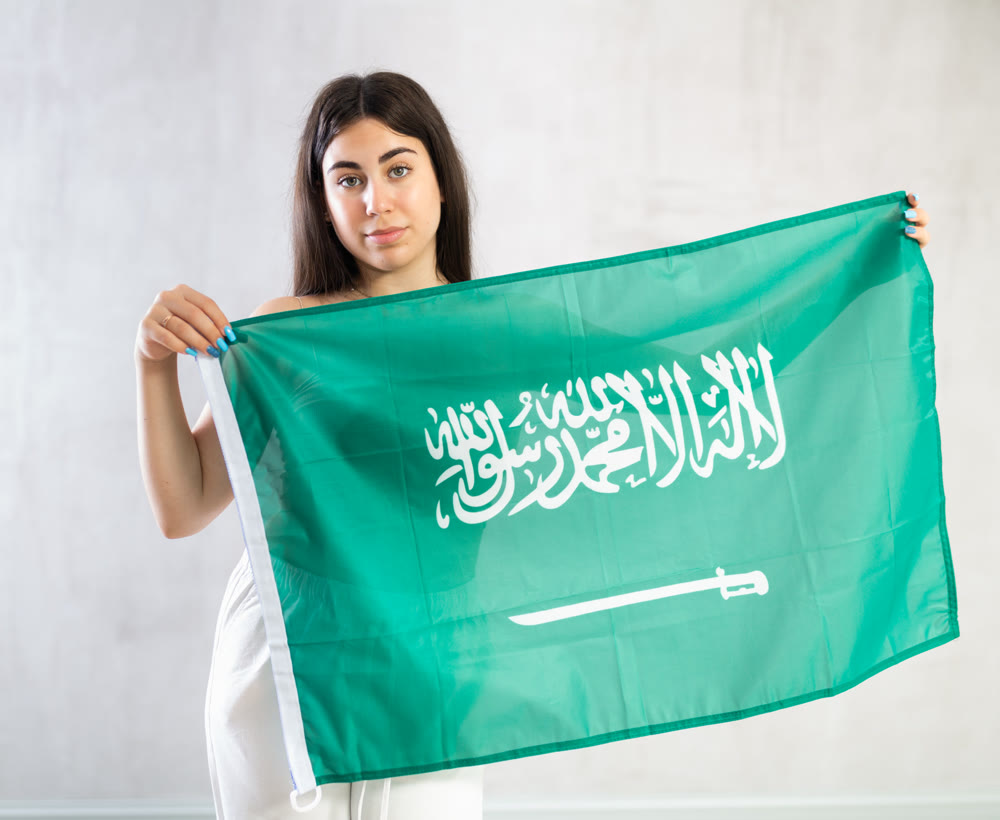 Young woman with flag of Saudi Arabia posing in studio