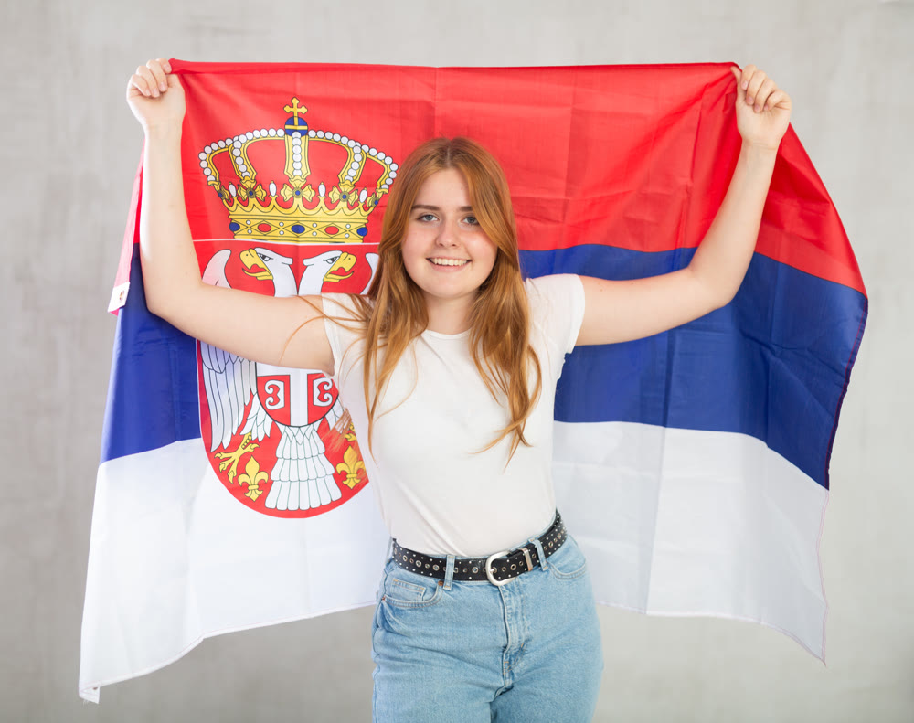 Portrait of positive young woman with flag of Serbia