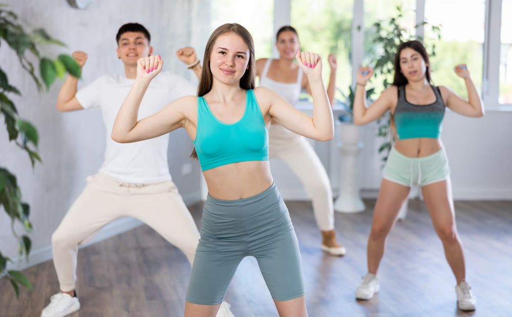 Girl performing krump movements with group of teenagers in studio