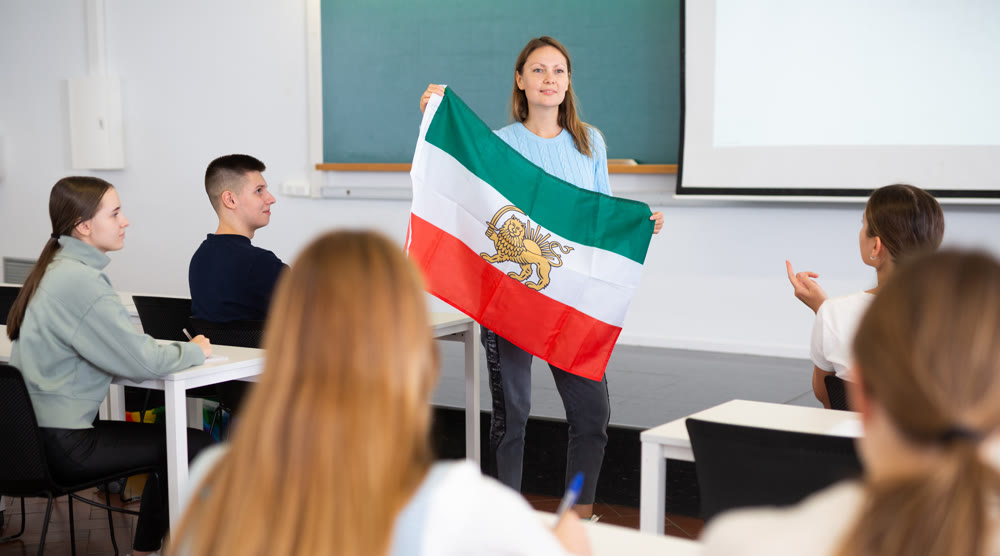 Adult female teacher showing Iranian flag to students