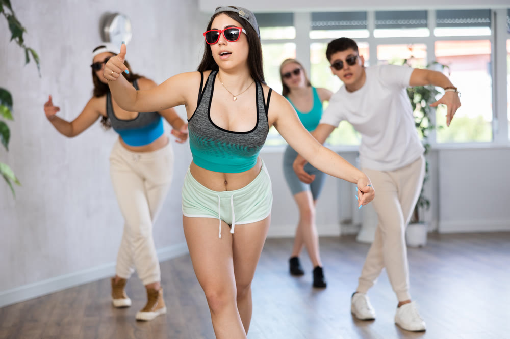 Expressive teen girl krumper dancing with group of teenagers in studio