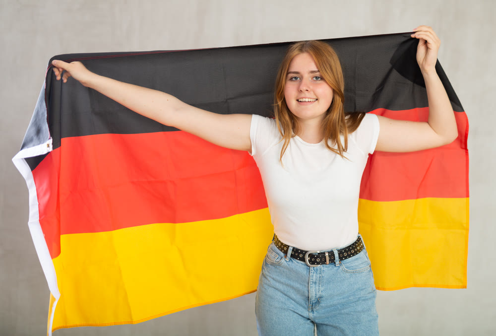 smiling girl in arms raised above head holds canvas of national flag of Germany