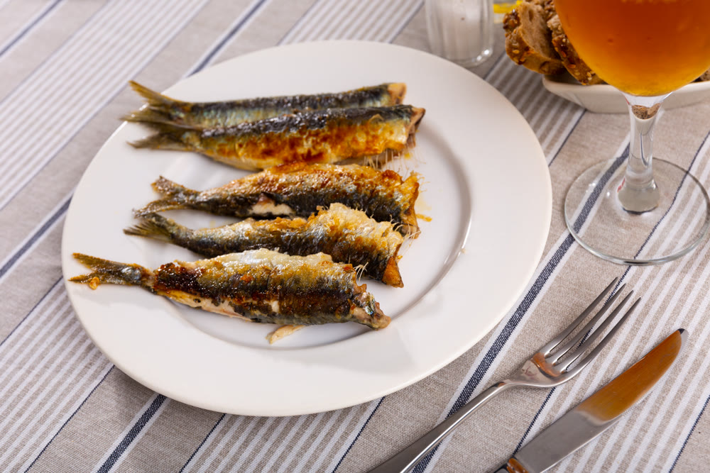 Grilled sardines served with bread and glass of beer