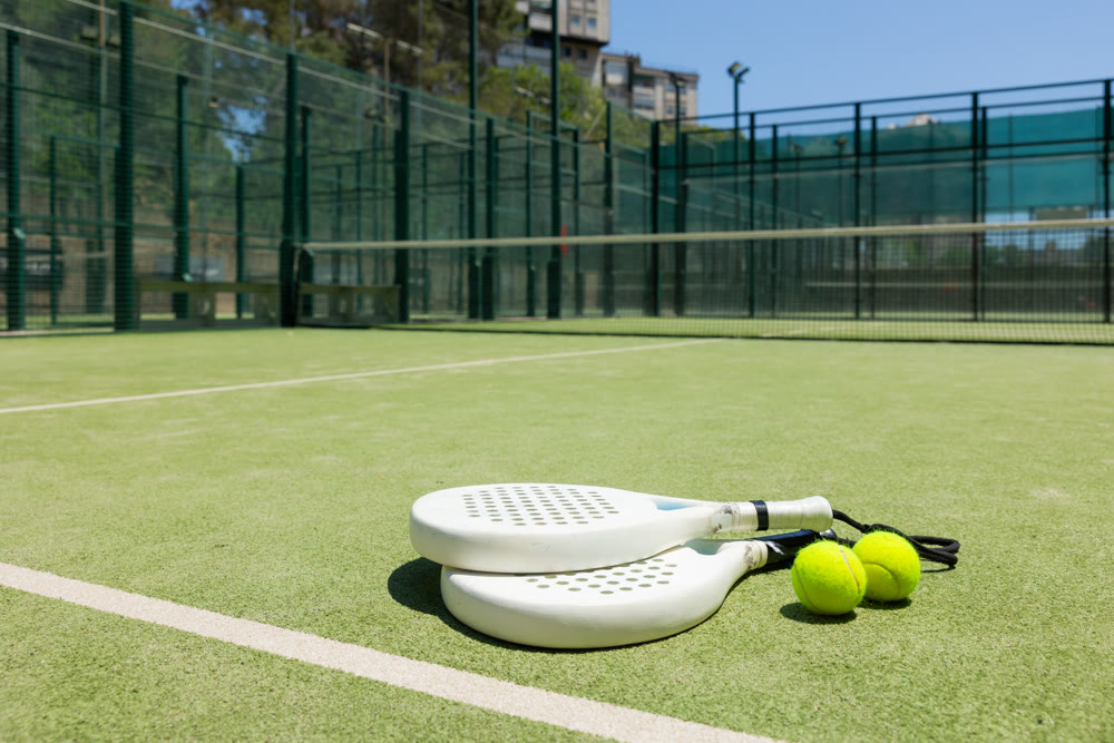 Rackets and balls for playing padel on an outdoor tennis court