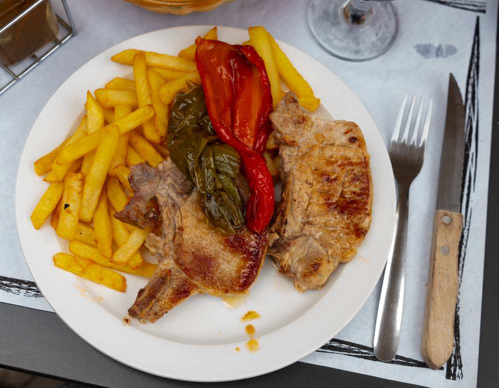 Baked pork chops served with french fries and baked peppers