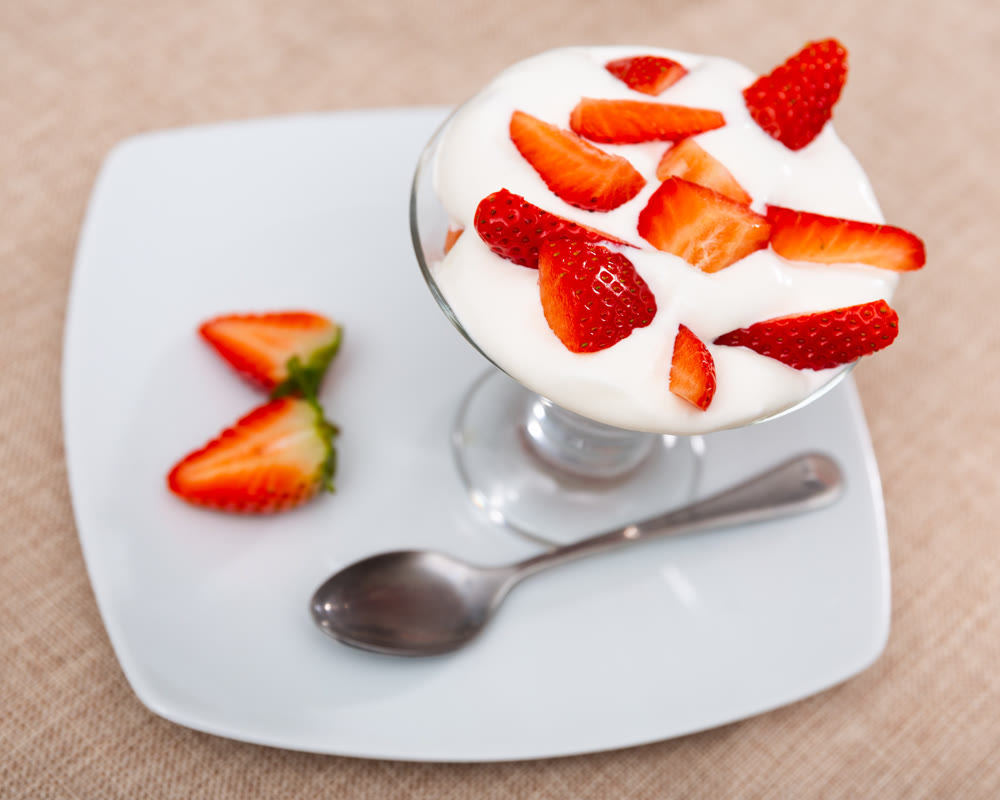 Whipped cream with strawberries in glass cup
