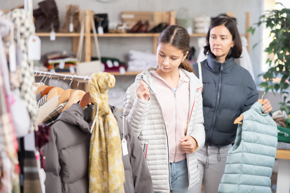 Teenage girl with her mother try on down jacket