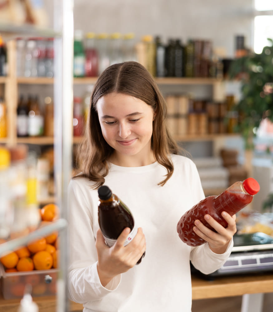 Teenage girl chooses pomegranate and tomato juices