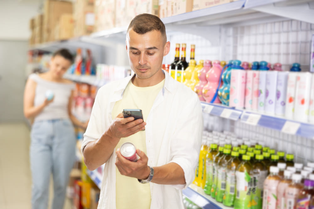 Male buyer reads QR code from aluminum can of drink in chinese supermarket
