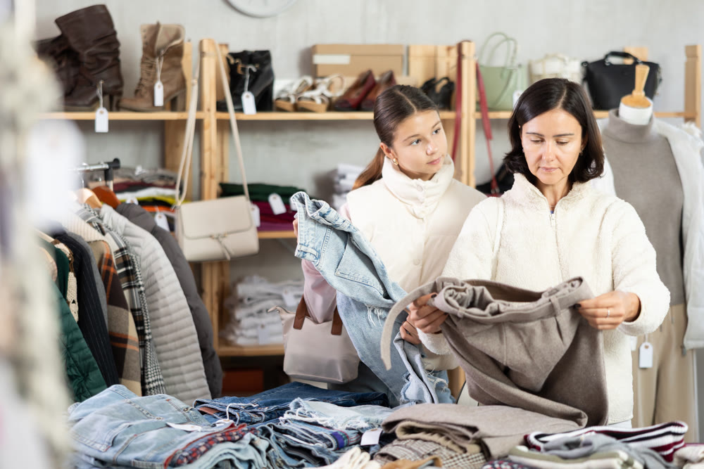 Adult woman and teenage girl choose jeans and trousers