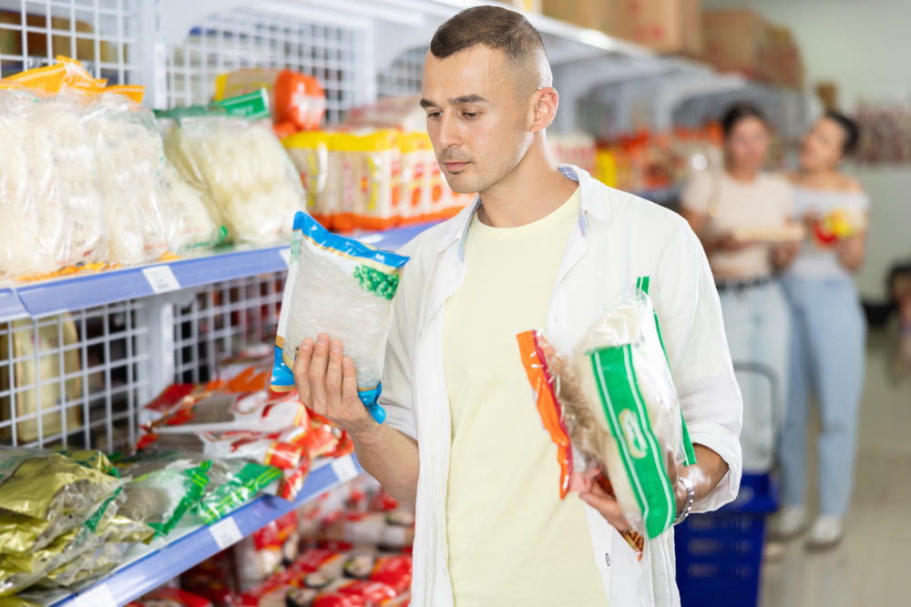 Male shopper choosing traditional Chinese noodles in supermarket