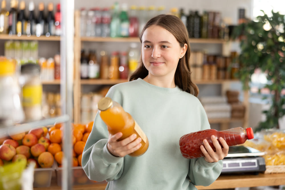 Teenage girl chooses peach and tomato juices