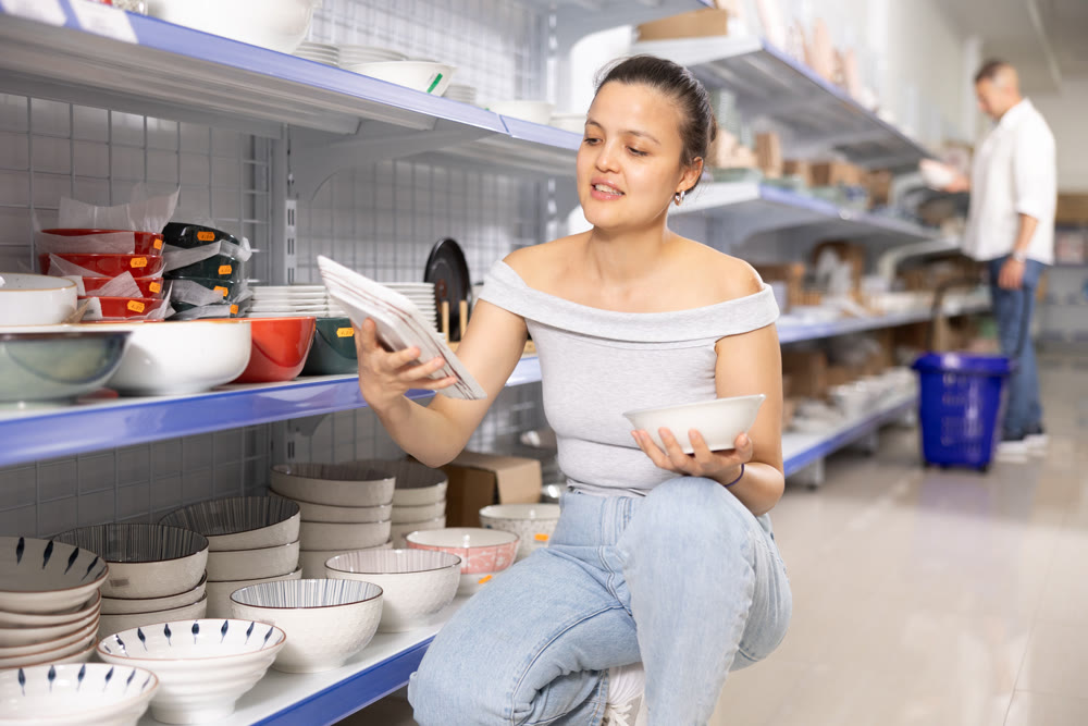 Woman looking for new plates at store of household goods