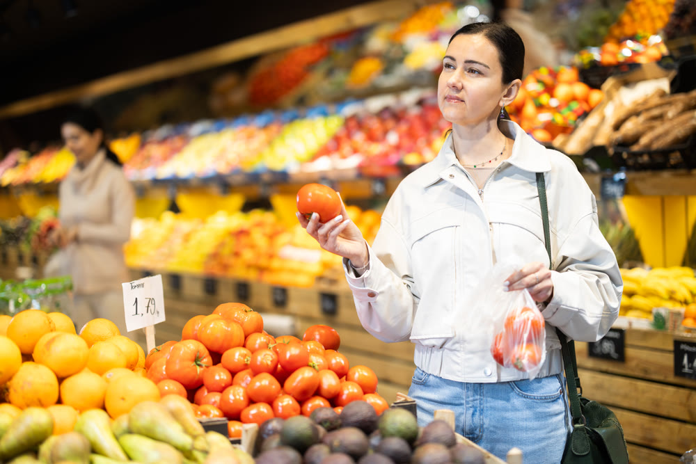 Adult woman choosing tomatos in vegetable shop