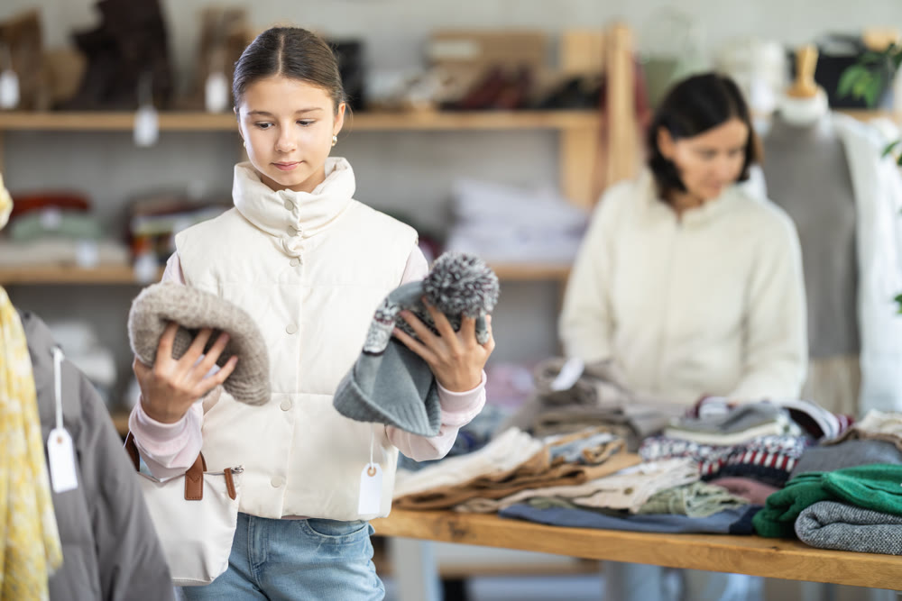 Teen girl looks at products in store and selects hat. Family shopping