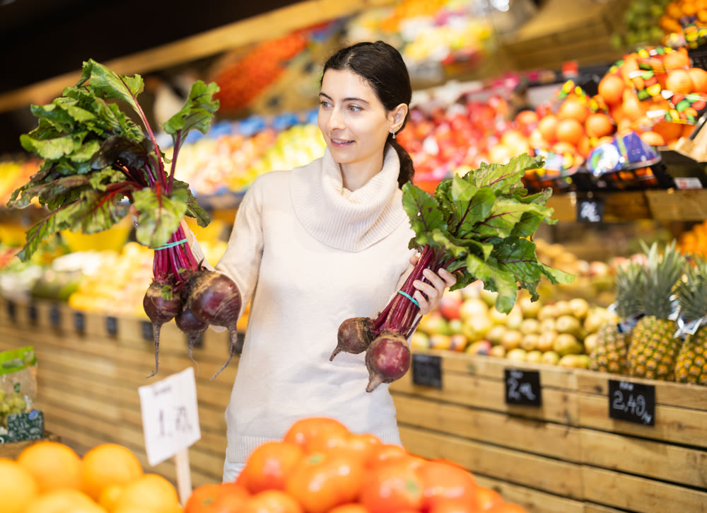 Young woman choosing beets in vegetable shop