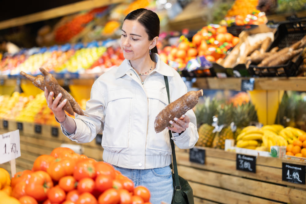 Positive woman shopping in grocery supermarket - choosing yucca root