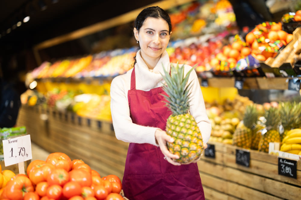 Saleswoman with pineapples for the supermarket